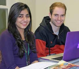 two students at a computer smiling